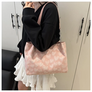 Detail of pink tote bag with white heart embroidery and stylish metal chain strap