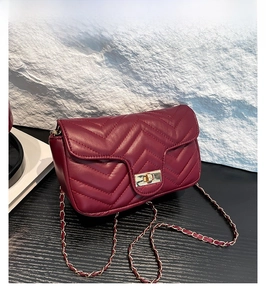 Détail du sac bandoulière bordeaux avec matelassage en V et fermoir rotatif doré élégant