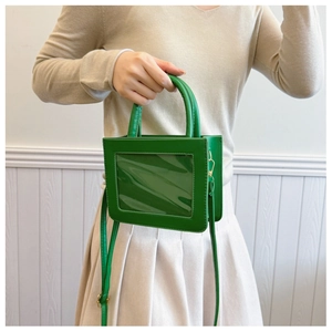 Détail du mini sac vert en similicuir avec fente transparente et boucles dorées