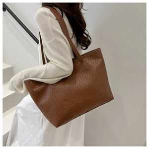 Brown embossed leather tote bag on shoulder with textured finish on a spiral staircase