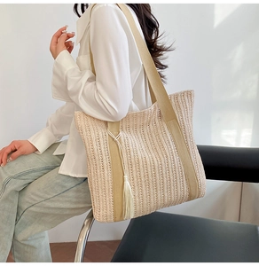 Dettaglio della borsa tote in paglia intrecciata beige con nappa e trama verticale