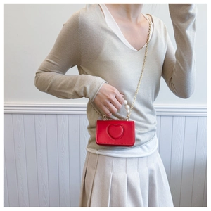 Detailed view of red heart leather bag with pearl handle and gold chain on model