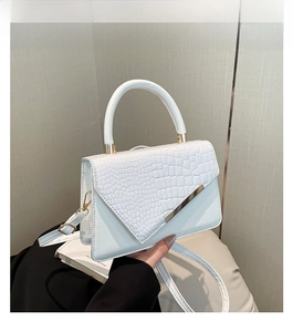 Detailed view of white crossbody bag with crocodile texture and gold metal accents