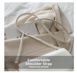 Detail of adjustable shoulder strap with gold metal buckle on white leather saddle bag