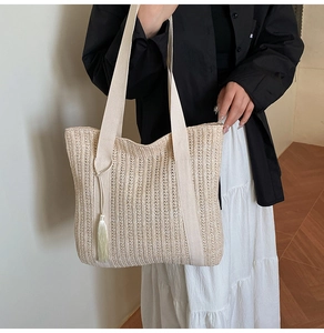 Dettaglio della borsa tote in paglia intrecciata a mano con trama verticale e frange laterali