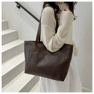 Close-up of the brown embossed texture and handle detail on a large tote bag