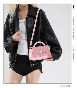 Détail du sac à main rose en cuir avec texture tressée et fermoir rotatif doré