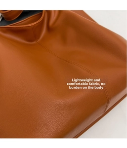 Gros plan sur la texture du cuir marron et les doubles coutures de ce sac cabas