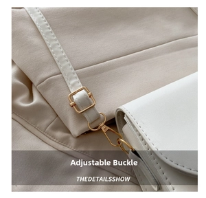 Close-up of golden metal adjustment buckle and snap hook on cream leather handbag strap