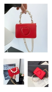 Détail du mini sac rouge avec cœur en relief et poignée élégante en perles