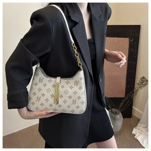 Detailed shot of cream monogram handbag with vintage print and gold chain strap
