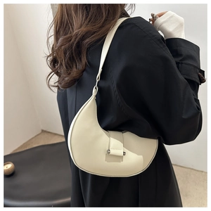 Minimalist beige crescent hobo bag shown on model wearing black coat for daily commute