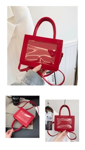 Detail of red glossy leather bag with clear window panel and detachable shoulder strap