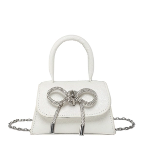 White mini trapezoid handbag with rhinestone bow and chain strap on white background