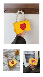 Détail du mini sac jaune avec poignée en perles et cœur rouge sur bandoulière