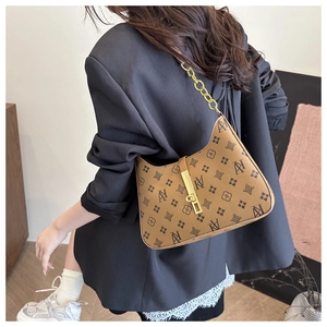 Detailed side view of brown patterned underarm bag with gold chain strap on a model