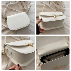 Detail view of white minimalist crossbody bag showing golden metal clasp and internal storage