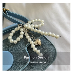 Détail du sac en jean avec chaîne de perles en nœud et pendentif en cœur argenté