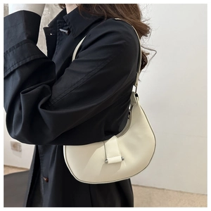 Detail of off-white hobo crescent bag with silver hardware on a black coat outfit