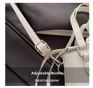 Detail of adjustable white lychee leather shoulder strap with silver metal buckles