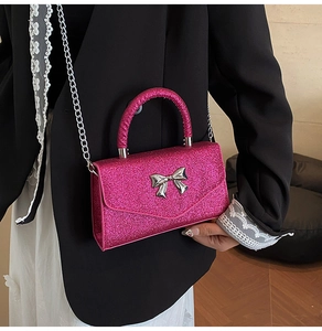 Gros plan sur la texture à paillettes fuchsia et le nœud argenté du mini sac à main chic