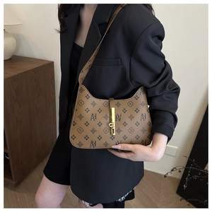 Brown vintage hobo bag with letter print and gold buckle styled in a retro setting