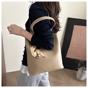 Dettaglio della borsa tote beige con sciarpa di seta vintage e testo moda sulla superficie