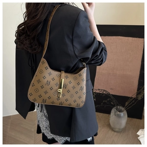 Close-up of vintage brown monogram shoulder bag with gold metal clasp on a model