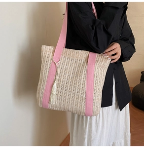 Dettaglio della borsa tote in paglia intrecciata con spalline rosa e nappa decorativa