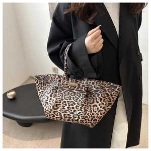 Detailed view of leopard print tote bag with golden metal hardware and premium texture