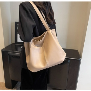 Détail d'un grand sac cabas beige porté avec un blazer noir pour un look professionnel