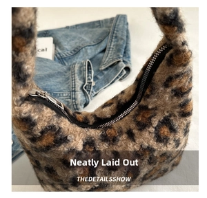 Gros plan d'un sac hobo pelucheux à motif léopard avec fermeture éclair en métal argenté