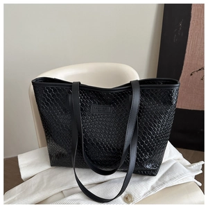 Close-up of black woven leather tote bag with fine texture and brand logo detail