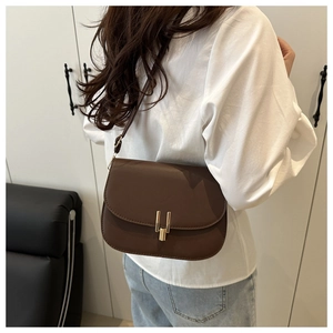 Detail view of dark brown saddle bag with golden metal buckle and minimalist strap
