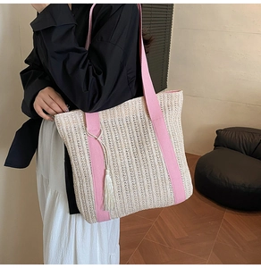 Dettaglio della borsa tote in paglia intrecciata con spalline rosa e nappe bianche laterali