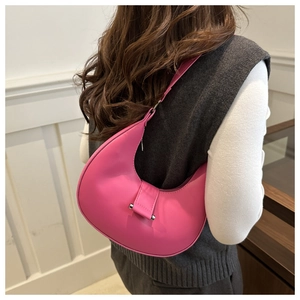 Side view of a bright pink crescent hobo bag with silver buckle worn by a model