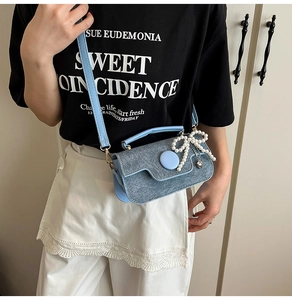 Détail du mini sac en denim bleu avec pendentif nœud en perles et bandoulière réglable