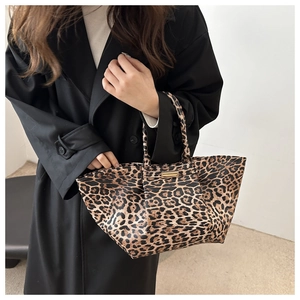 Close-up of leopard print tote bag featuring double handles and gold metal hardware