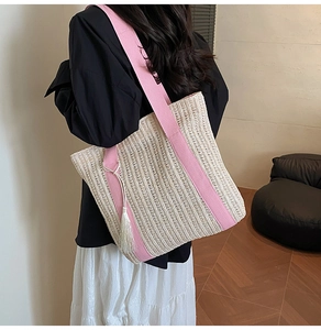 Dettaglio borsa tote intrecciata con spalline rosa e nappe bianche decorative