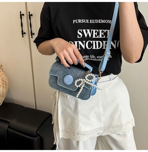 Détail du sac bandoulière bleu clair en denim avec nœud perlé et boucle ronde