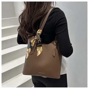 Dettaglio della borsa tote marrone scuro con foulard di seta e fibbie metalliche