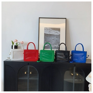 Detail view of five colorful ita bags with clear windows for charms on a display shelf