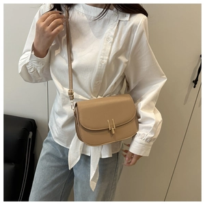 Detail of elegant apricot saddle bag featuring a matte finish and gold-tone metal buckle