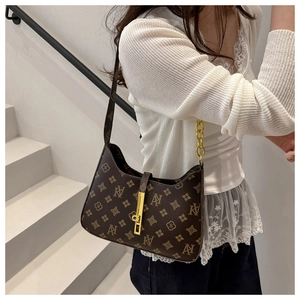 Detail of dark brown faux leather underarm bag with vintage floral pattern and metal lock