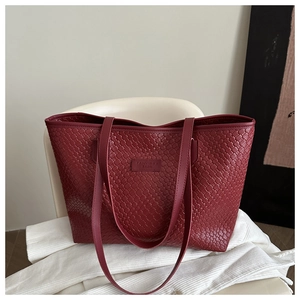 Detailed close-up of woven wine red tote bag texture and embossed logo leather patch