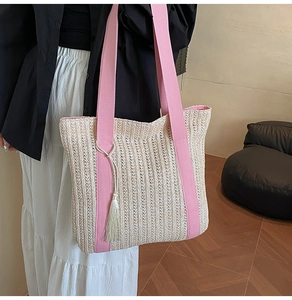 Dettaglio della borsa tote in paglia con manici rosa e nappa bianca per vacanze estive