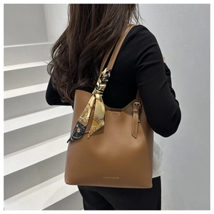 Close-up of brown faux leather tote bag with decorative vintage silk scarf on the strap
