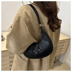 Detail shot of a black leather crescent hobo bag styled with a stylish wool coat
