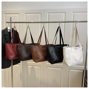Detailed view of large woven tote bags in five colors hanging on a metal display rack
