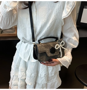 Détail du petit sac carré gris avec boucle ronde et pendentif nœud en perles